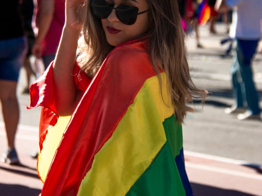 woman holding rainbow coloured flag