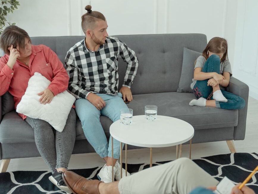 a couple sitting on a couch with their daughter at a therapy session